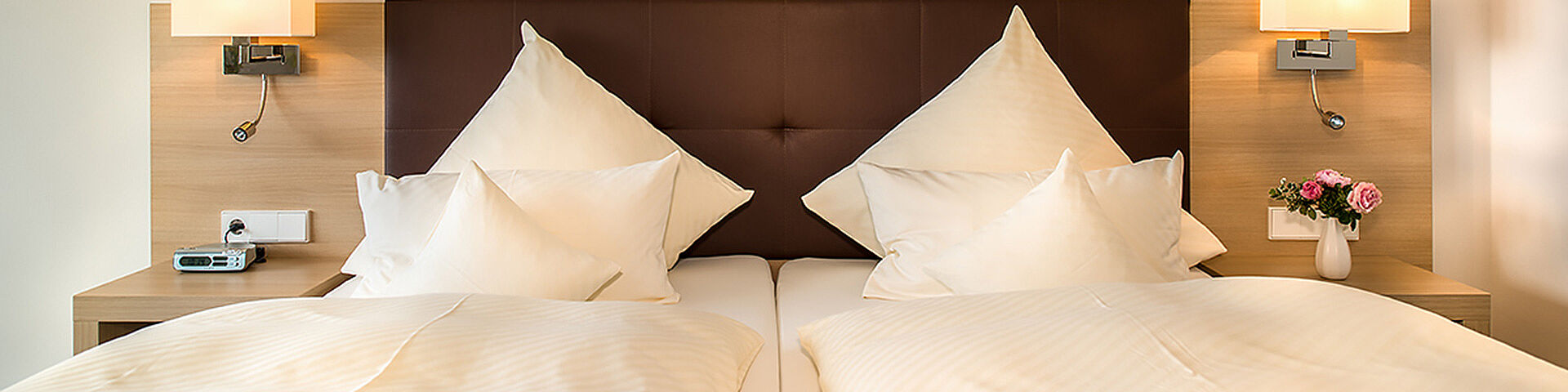 Ein Doppelbett mit Kissen und Bettdecke ist zu sehen.