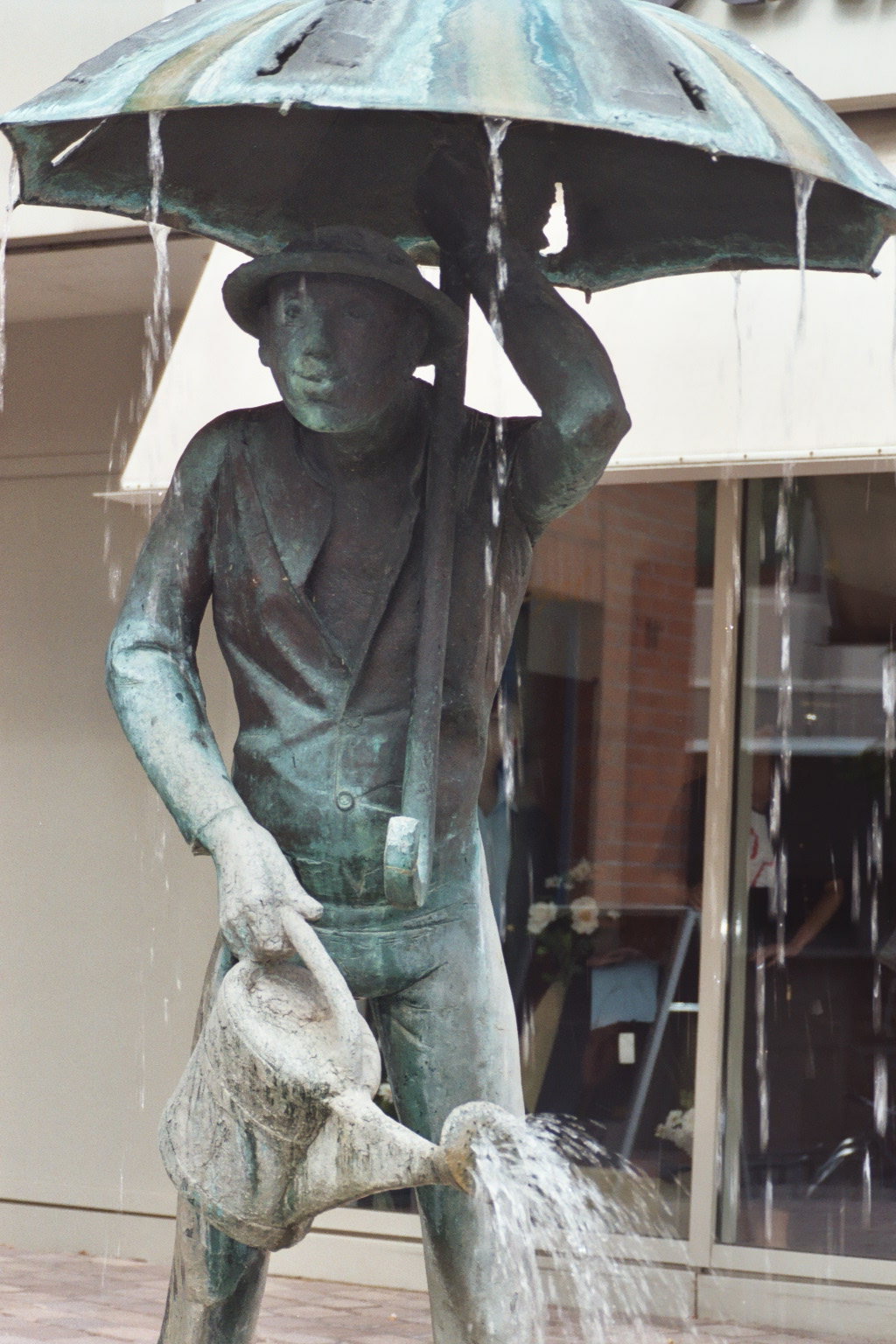 Eine Brunnenfigur mit Regenschirm und Gießkanne ist zu sehen.