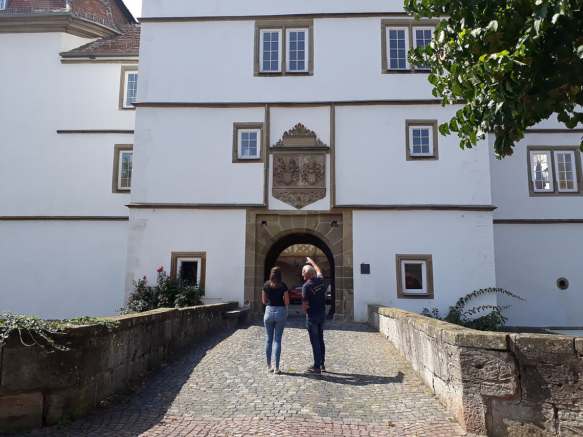 Ein Führer steht mit einer Besucherin vor dem Pfedelbacher Schloss.