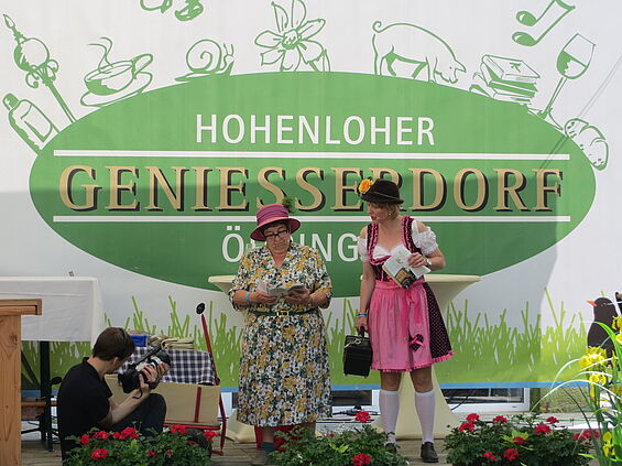 Zwei verkleidete Damen stehen auf der Bühne des Genießerdorfes.