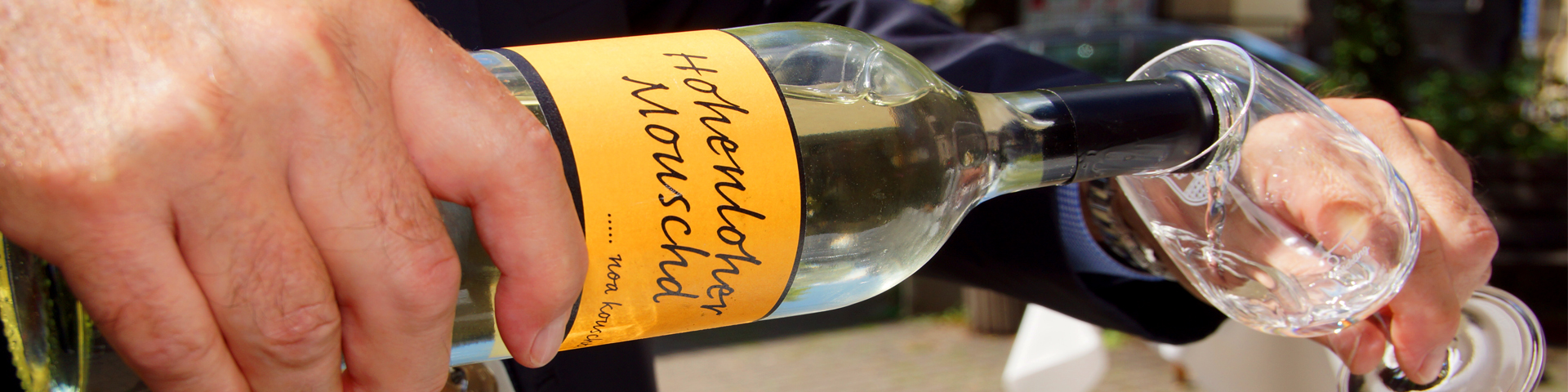 Eine Most-Flasche mit gelbem Etikett aus der ein Weinglas gefüllt wird, ist zu sehen.