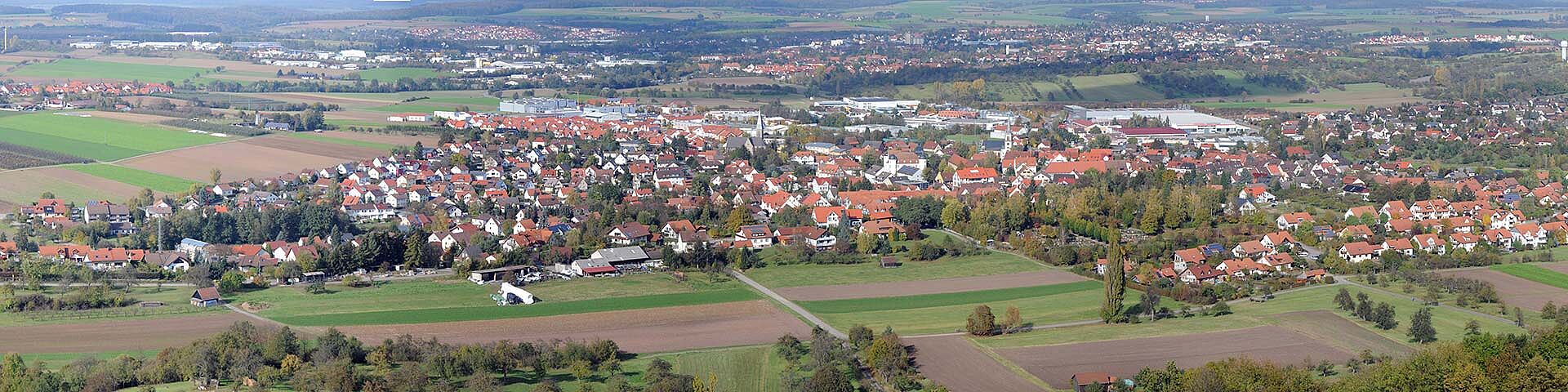 Die Gebäude von Pfedelbach sind aus der Höhe zu sehen sowie Felder, Wiesen und Bäume.