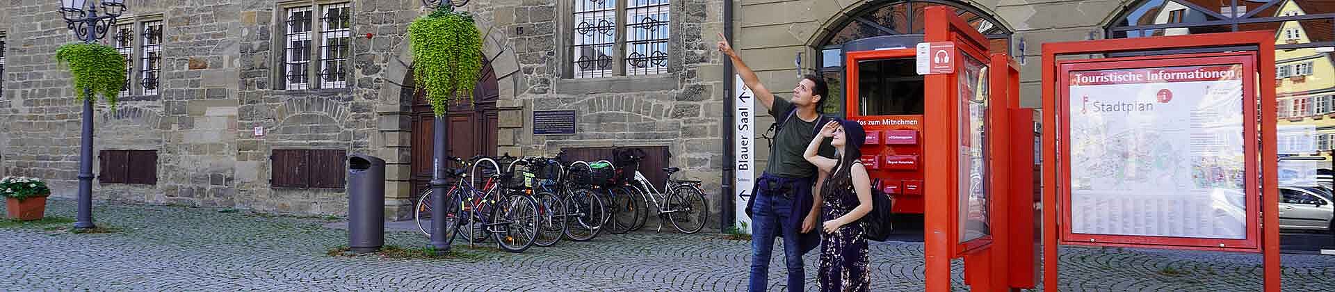Zwei Touristen stehen an einem Infopunkt vor dem Öhringer Rathaus.