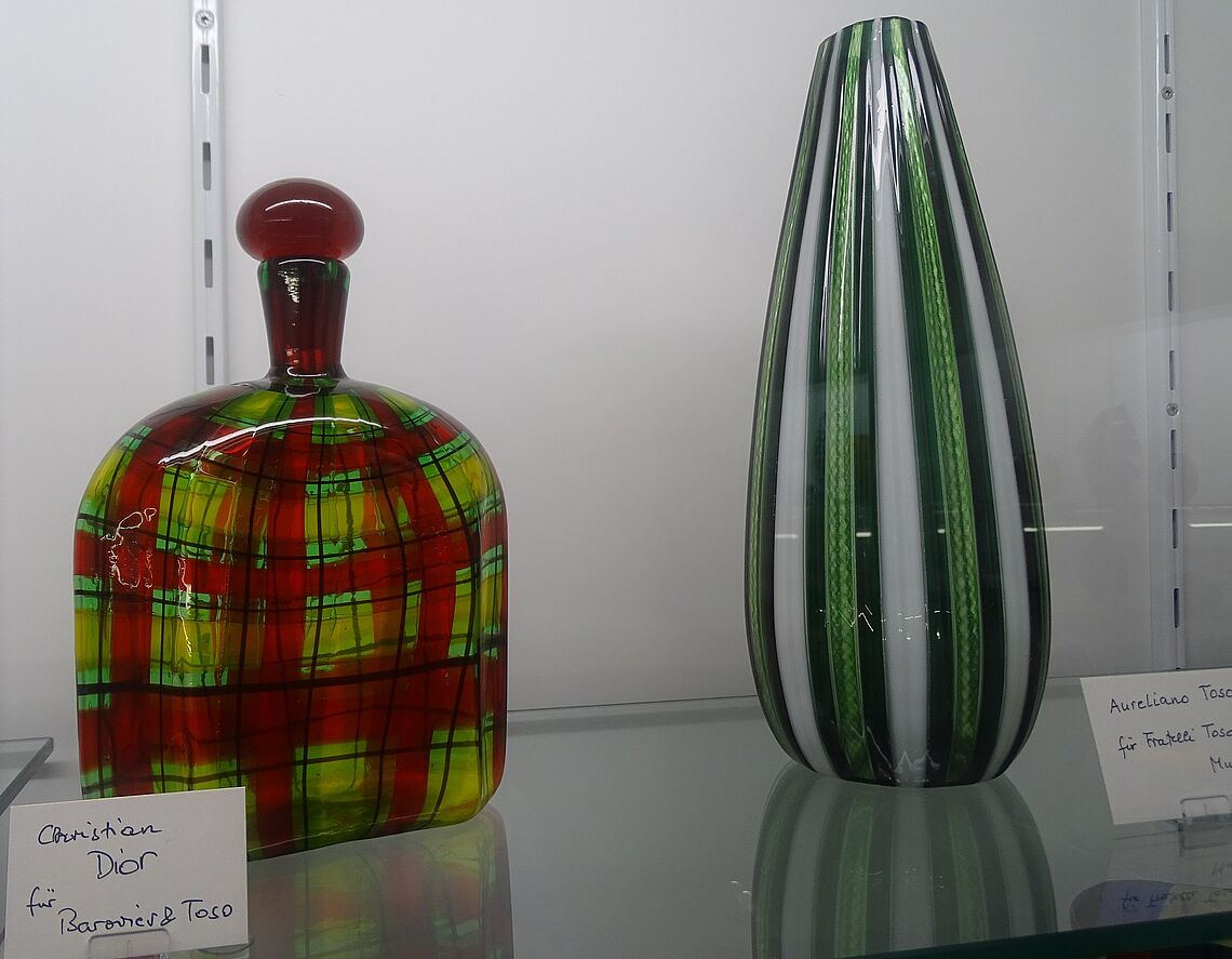 Eine karierte Glasflasche mit Stopfen ist links zu sehen, eine gestreifte Glasvase rechts.
